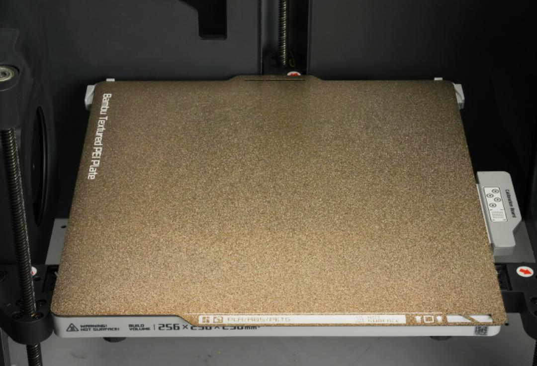 Завершальний етап встановлення: золотиста пластина Bambu Lab Textured PEI Plate щільно прилягає до магнітної основи 3D-принтера серій X1, P1 або A1.