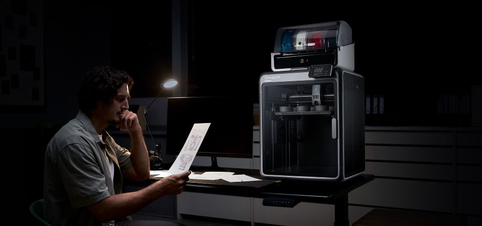 Невероятно тихая работа. Человек печатает на ноутбуке с принтером K2 на заднем плане, показывая тихую работу.